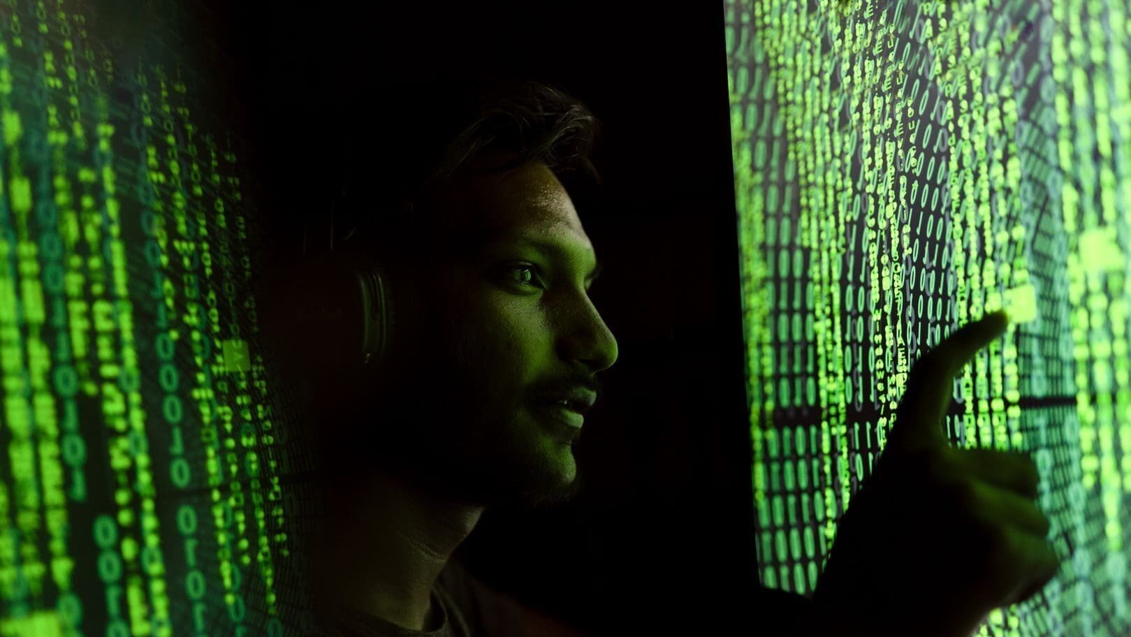 A person interacts with digital code on a screen, symbolizing cybersecurity technology.