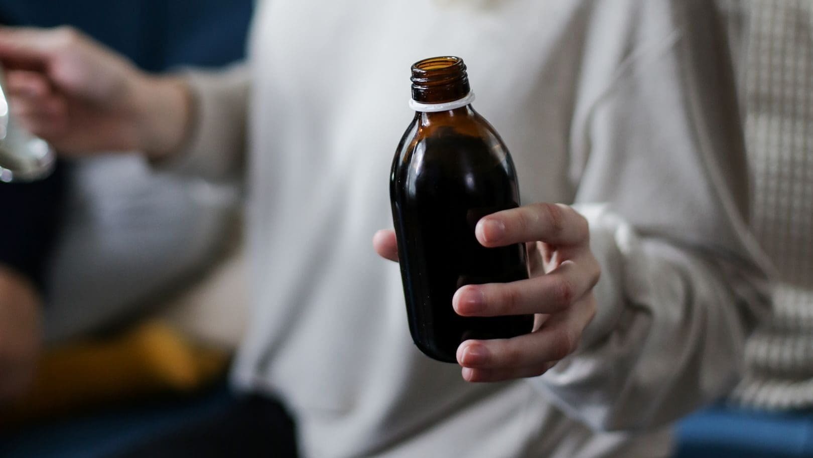 Close view of a person holding an amber medicine bottle, signifying health care and treatment.